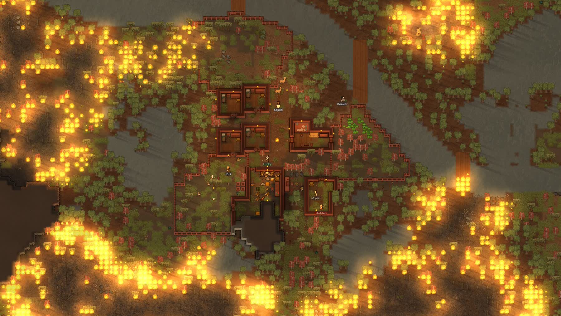 A forest fire spreading around a player-built RimWorld settlement